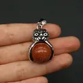 Ciondolo gufo in pietra dorata con cornice argento tenuto in mano per mostrare le dimensioni - pietra sabbia dorata