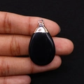 Close-up of black teardrop stone pendant with silver metal bail held in fingers - Black Agate (Silver Cap) / Black