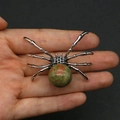Spider shaped unakite stone pendant with silver metal detailing held in hand - 34x47mm, 14g / Unakite