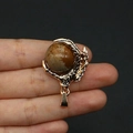 Golden dragon claw pendant featuring a brown striped natural stone bead on black background - Jasper