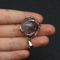 Golden dragon claw pendant featuring a round purple gemstone held by a hand - Purple Crystal