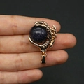 Golden dragon claw pendant with blue goldstone sphere held in hand on black background - Blue Sandstone