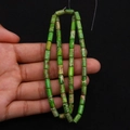 Macro view of green emperor stone cylinder beads with natural veins held in hand - 4x8mm / Size 11