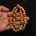 Close-up of natural emperor stone beads with unique brown marbling on hand - 4mm / Cream Mottled