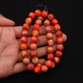 Detail view of round orange-red imperial stone beads with white webbed veins held by hand - 4mm Size / Orange Red (No. 1)