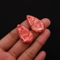 Macro shot of two teardrop-shaped red marble stone pendants with unique natural patterns - No.1 (Red And White Marble)