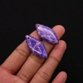Détail macro de deux pendentifs losanges en pierre naturelle violette tenus par la main - Violet Blanc Filamenteux (N° 10)