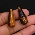 Dettaglio di perle a goccia in pietra occhio di tigre lucida tra le dita - 10x25mm, 5g / Occhio di tigre