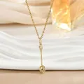 Detailed view of a golden crown spoon pendant on a delicate chain over a ceramic plate - Crown Spoon Style (XL02468)
