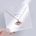 Nahaufnahme der goldenen Halskette mit rosa herzförmigem Kristallanhänger im Saturn-Design - Rosa Herz Planeten Stil