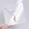 Detailaufnahme eines goldenen Schmetterlings-Anhängers mit Zirkonia-Steinen und weißer Perle - Wellen-Perlen-Stil