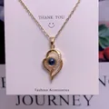 Makroaufnahme einer goldenen Herz-Halskette mit blauem Stein und Zirkonen auf Dankeskarte - Herz Design(TY009)