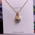 Detailed macro view of gold-plated flame pendant with a deep blue bead and white crystal accents - Flame Shape (TY0041) / Gold