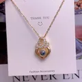 Detailansicht der goldenen Projektionskette mit Kristallen und blauem Stein-Anhänger - Verschlungene Ringe Design(TY0077)