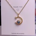 Detail view of gold chain necklace with a crescent moon pendant and dark blue projection stone - New Moon Style (TY0048) / Gold