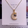 Detailed view of a gold crescent moon pendant set with zircons and a central grey stone - Moon Shape (TY0051) / Gold