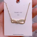 Macro shot of gold infinity necklace pendant with sparkling zircon on a white gift card - Shiny Pave Infinity Style (SQ009)