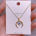 Detailansicht der goldenen Evil-Eye-Halskette mit Mondsichel-Anhänger auf Karte - Goldener Mondsichel-Auge-Anhänger (YJ005)