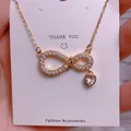 Close-up of infinity symbol and heart pendant with sparkling cubic zirconia on gold necklace - Intertwined Heart Infinity Style (SQ0010)