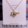 Close-up of golden heart and arrow projection necklace on a white display card - Cupid's Arrow Shape (TY0053) / Gold