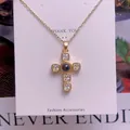 Makroansicht des goldenen Kreuzanhängers mit schwarzer Perle und Kristallen auf einer Karte - Prachtvolles Kreuz Design(TY0082)