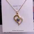 Detail of gold heart projection necklace with blue stone and sparkling zircon accents - Asymmetric Heart Style (TY0055) / Gold