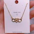 Macro shot of gold infinity heart necklace with zircon inlay on display card - Interlocked Heart Infinity Style (SQ0014)