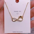Macro view of gold infinity necklace with crown detail and crystals on display card - Crown Infinity Style (SQ0015)
