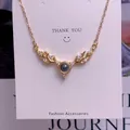 Close-up of golden antler necklace with diamonds and projection stone on gift card - Elegant Antler Style (TY0058) / Gold