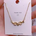 Macro shot of gold infinity arrow pendant with white zircons on a white display card - Arrow Heart Infinity Style (SQ0016)
