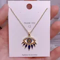 Detail eines goldenen Evil Eye Anhängers mit blau-weißen Kristallen an einer Kette - Goldener Augenförmiger Anhänger Im Mediterranen Stil (YJ0018)