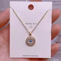 Nahaufnahme der goldenen Evil Eye Halskette mit blauen Zirkonen auf einer Karte - Goldgelber Runder Augen-Strassanhänger (YJ0023)