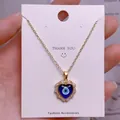 Detailansicht eines herzförmigen Evil Eye Anhängers mit glitzernden Zirkonia-Steinen - Goldener Herz-Böses-Auge-Strassanhänger (YJ0027)