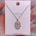 Makroansicht der goldenen Hand der Fatima Halskette mit Zirkonia und blauem Auge - Goldene Hamsa-Hand Mikro-Strass Blaues Böses-Auge-Anhänger (YJ0030)