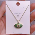Nahaufnahme der goldenen Evil-Eye-Halskette mit grünen Zirkonia-Steinen auf der Karte - Goldener Augenförmiger Grün-Weißer Strassanhänger (YJ0032)