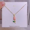 Gros plan du collier tulipe avec pétales roses et feuilles vertes sur carte de présentation - Style Tulipe Émaillée Rose (YJX0032)