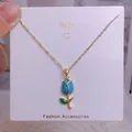 Détail d'un collier chaîne dorée avec pendentif fleur de tulipe en émail bleu sur carte - Style Tulipe Émaillée Bleue (YJX0036)