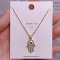 Detaillierte Makroansicht des goldenen Hamsa-Handanhängers mit Zirkonia und blauem Auge - Goldener Mikro-Strass Hamsa-Handanhänger (YJ0043)