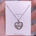 Detalle del collar de corazón plateado con grabado de Mom en una tarjeta de exhibición - Piedra de Doble Corazón Plateada (MOM12)