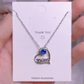 Detalle del colgante corazón con gema azul y letra 'mom' en cadena de plata - Corazón de Piedra Azul Plateada (MOM09)