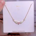 Détail macro du pendentif ailes de cœur doré avec pierre rose et diamants blancs - Style Pierre Rose Cœur Ailes Or (CB34)