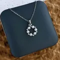 Gros plan d'un pendentif en perles et zircons sur une chaîne argentée et un coffret - Anneau de Perles Rond Argent (XL0603G)