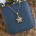 Détail du pendentif étoile dorée avec zircon cœur rose sur un écrin à bijoux bleu - Double Étoile Cœur Zirconia Rose Or (XL0605G)