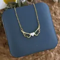 Détail du collier ailes d'ange dorées avec pendentif cœur sur une boîte à bijoux - Cœur d'Aile Coquille Or (XL0609)