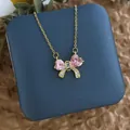 Détail d'un collier pendentif nœud rose en or dans un écrin de bijoux bleu élégant - Grand Nœud Zirconia Cœur Rose (XL0617A)