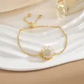 Dettaglio di un bracciale regolabile a girasole in oro con zirconi su un vassoio bianco - Bracciale Rotante Girasole Oro (SL0111)