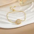 Dettaglio di un bracciale dorato regolabile con ciondolo a fiore in zircone su vassoio - Bracciale Rotante Fiocco di Neve Oro (SL0109)
