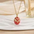 Close-up of red egg pendant with gold cross patterns and zircons on white stand - Bright Red Crossed Rhinestone Style (XL0653)