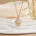 Detailed close-up of golden egg pendant with white enamel and sparkling zircon inlay - White V-Shape Wavy Style (XL0654)