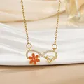 Detailansicht der goldenen Infinity-Halskette mit orangen Blumen und Herz-Anhänger - Blume Unendlichkeitssymbol
